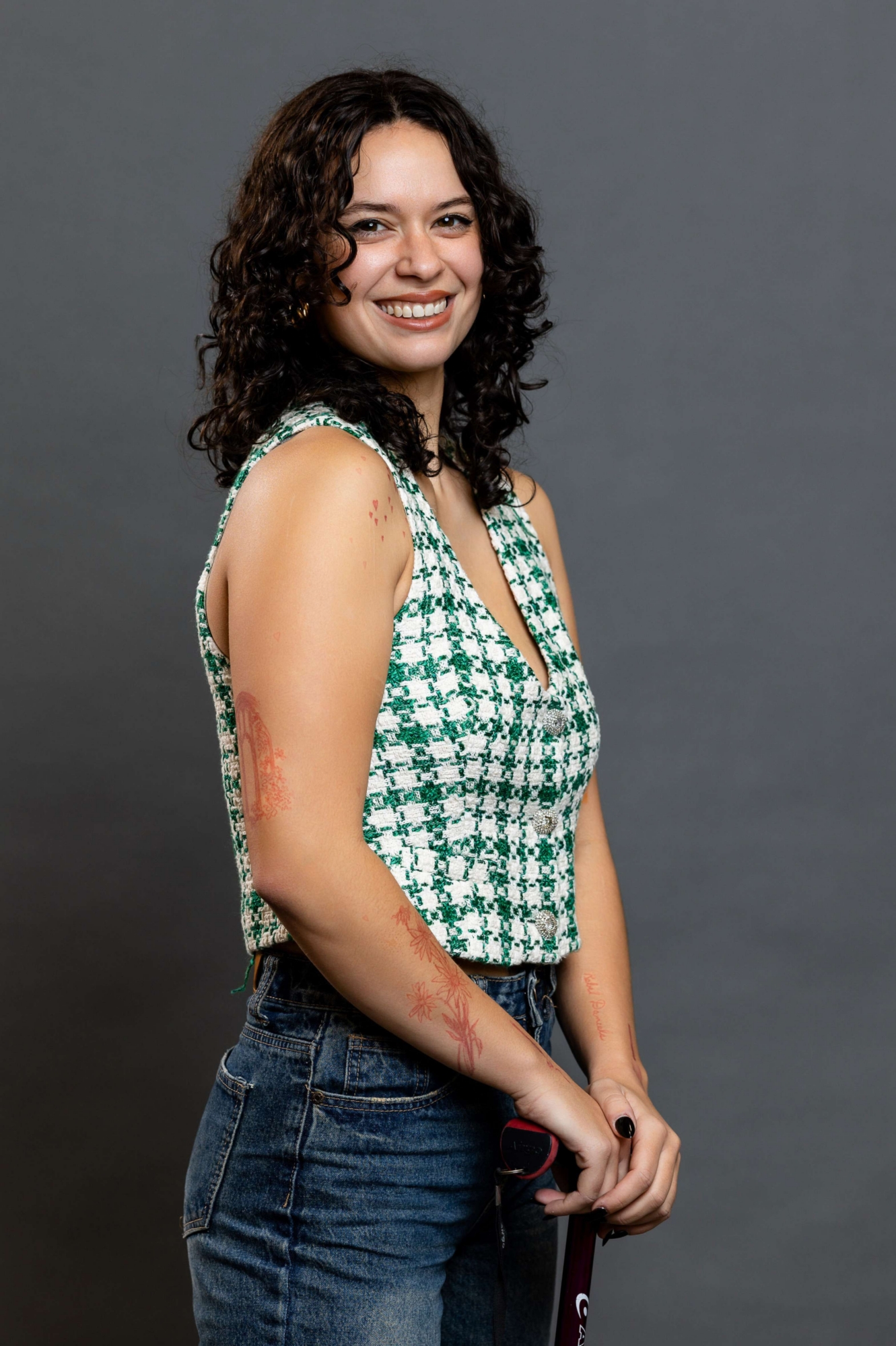 Maya posing for a photo with a grey background and a crutch.