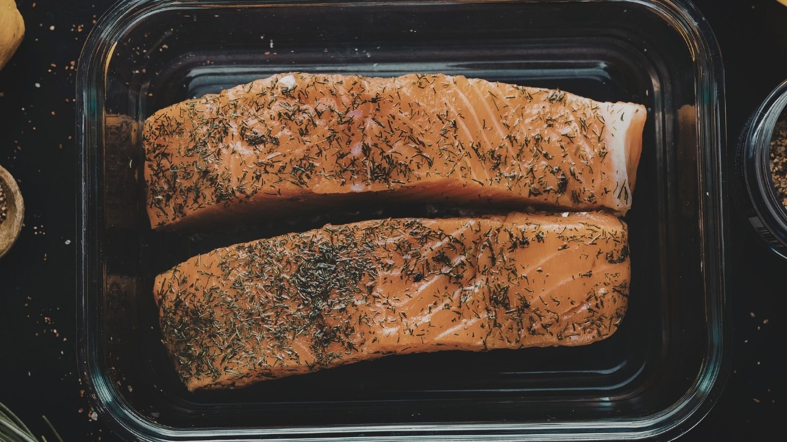 Oven-baked salmon in a clear dish and placed on a stove top