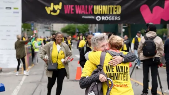 Participants cross the finish line at We Walk UHNITED and hug to celebrate.