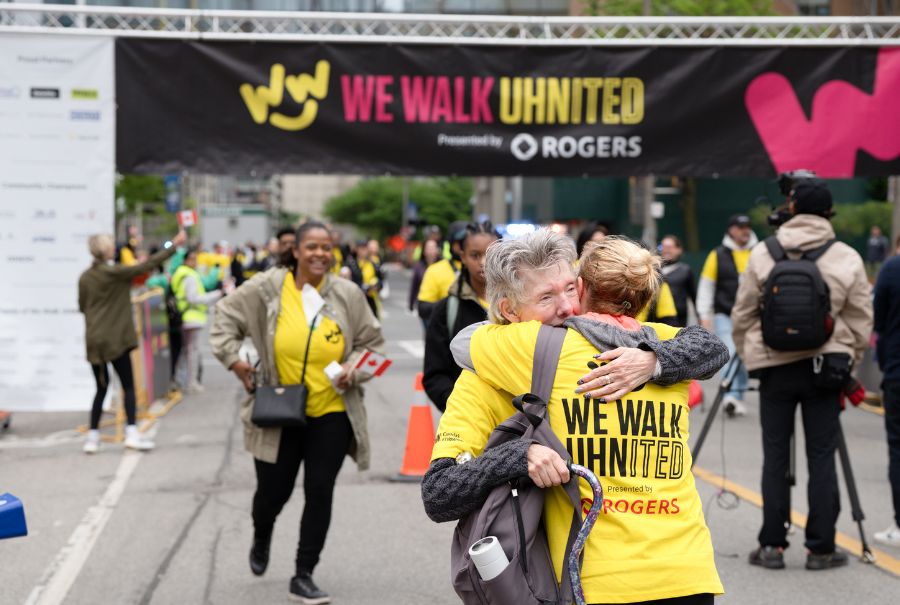 Participants cross the finish line at We Walk UHNITED and hug to celebrate.