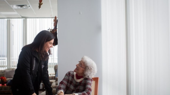 A support worker helping an older woman and has a conversation.