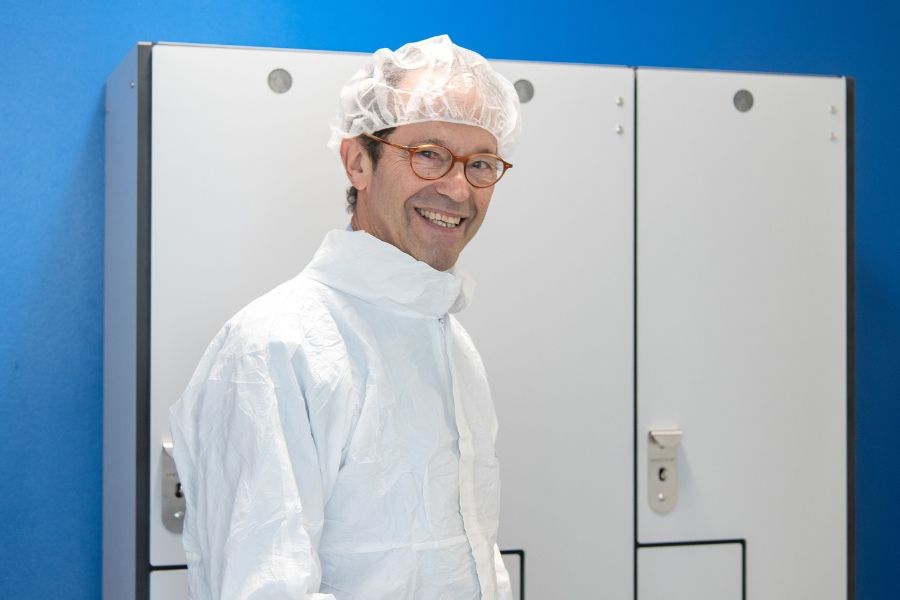 Dr. Michael Baker wearing PPE and smiling in front of lockers.