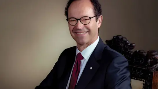 Dr. Michael Baker sitting in a chair wearing a suit while looking into the camera.