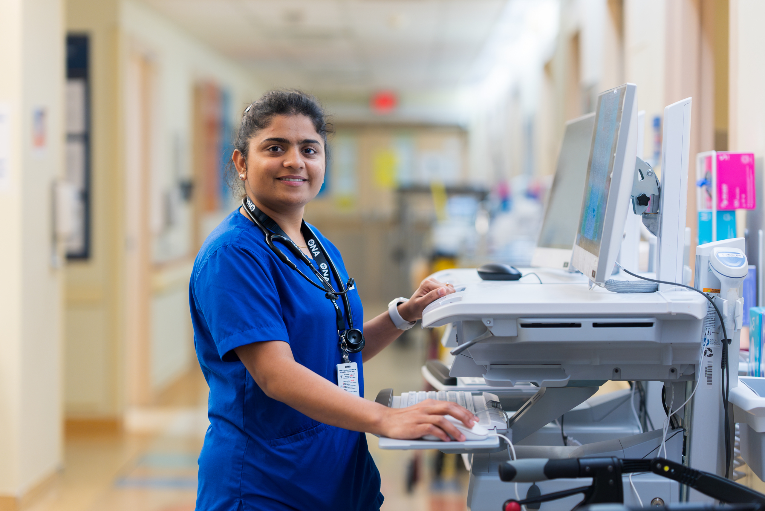  Healthcare professional using a mobile workstation to access or update patient information in a hospital setting.