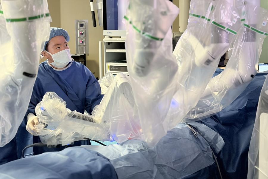 Dr. Michael Chua in an operating room at UHN's Toronto General Hospital with robotic equipment covered in protective plastic.