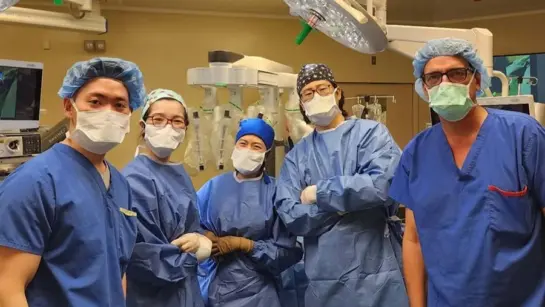 Members of UHN and SickKids teams in an operating room dressed in PPE and looking into the camera.