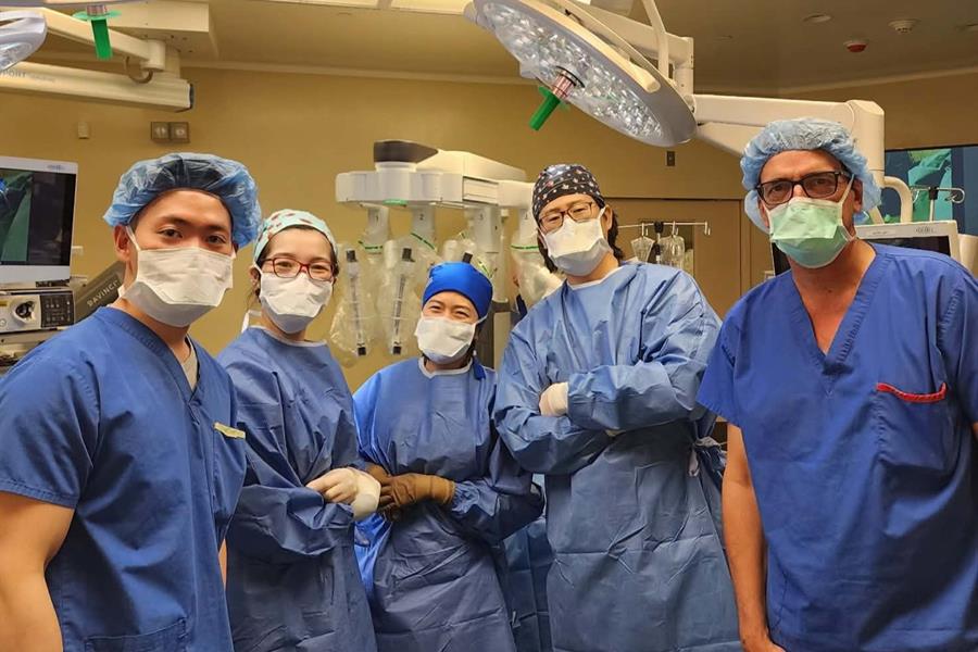 Members of UHN and SickKids teams in an operating room dressed in PPE and looking into the camera.