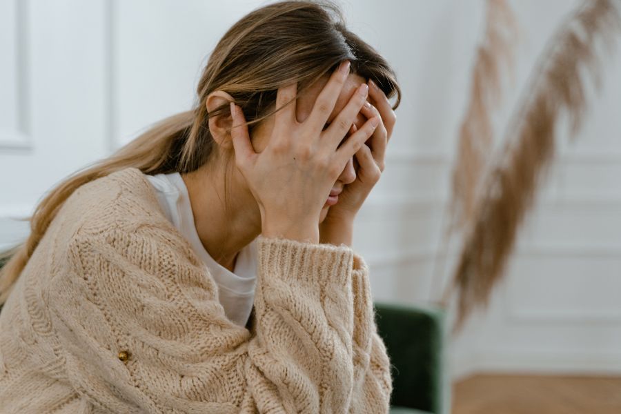 A lady holding her head while sitting down, showing symptoms of a concussion.