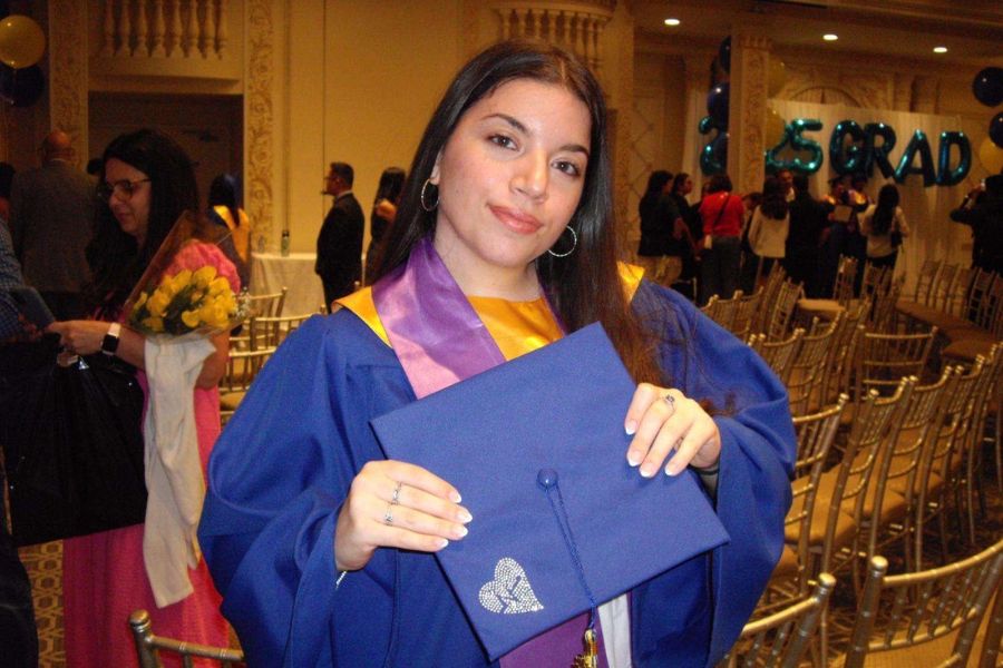 Maria Loschiavo at her graduation wearing her blue robe and empty ceremony chairs in the background.