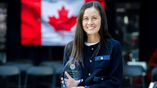 Dr. Jessica Liu holding an award in front of a Canadian flag.