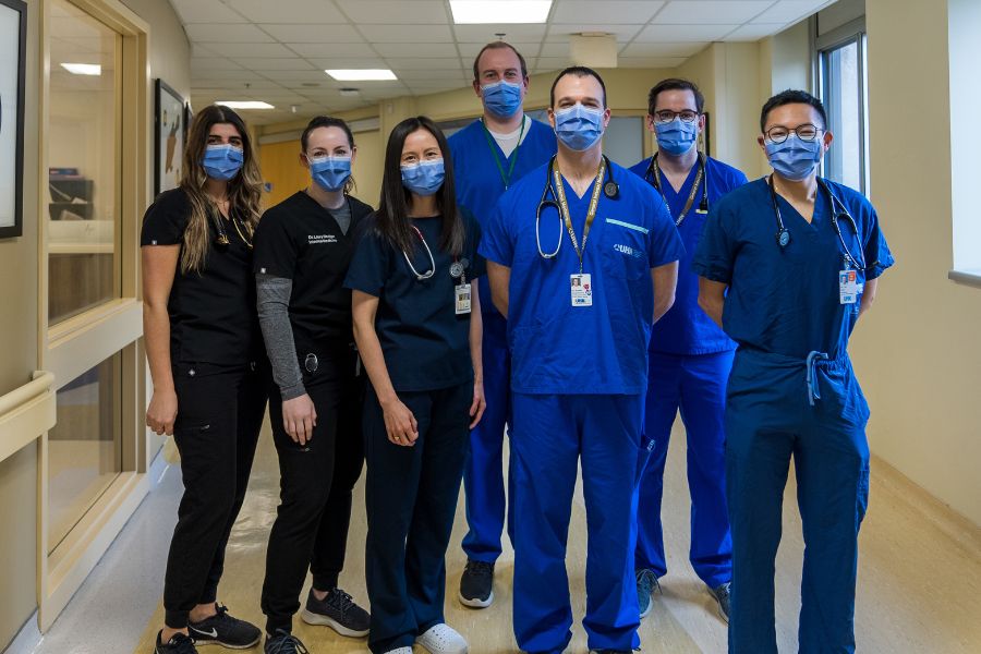 Internal Medicine group of physicians standing in their scrubs in a hallway at UHN all wearing their masks. 
