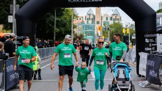 A family of participants of the Constantine Yorkville Run cross the finish line with a stroller.