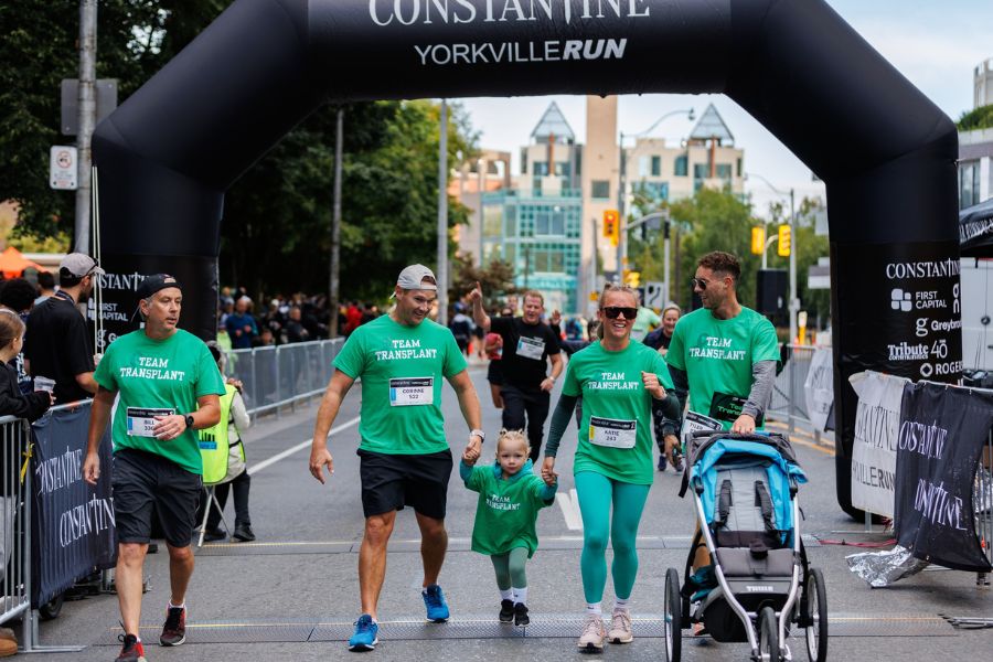 A family of participants of the Constantine Yorkville Run cross the finish line with a stroller.