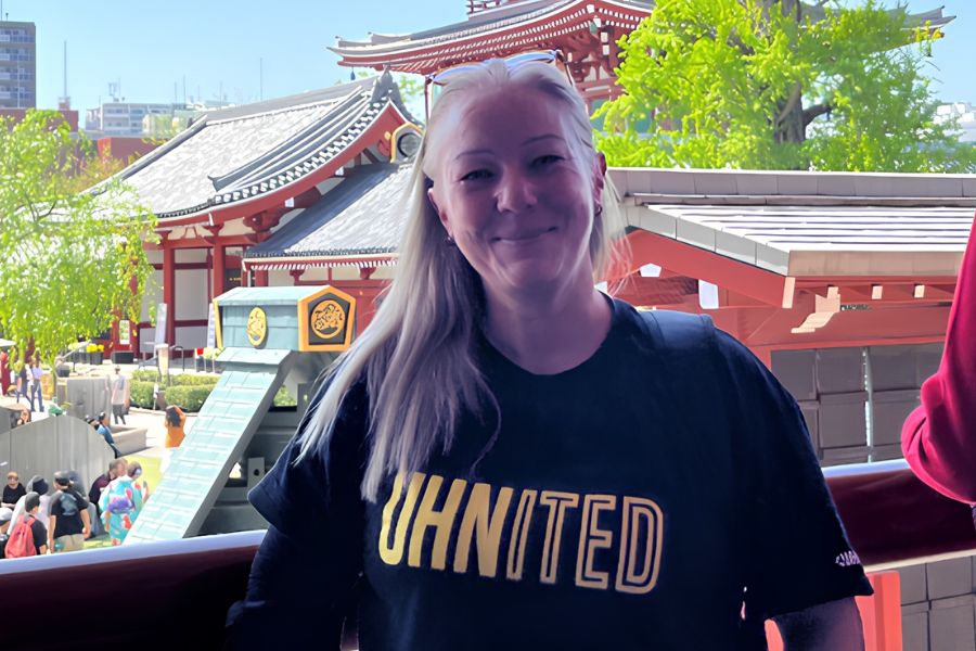 Claire Thomas standing next to a temple in Japan while wearing her black and yellow UHNITED t-shirt.