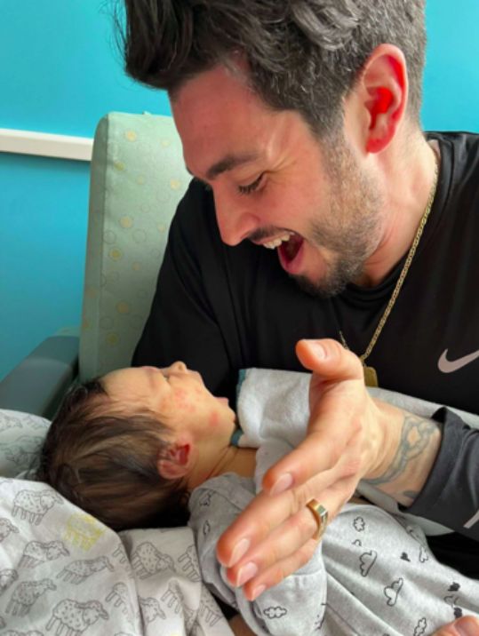 Joseph holding baby Camilla while both smiling.