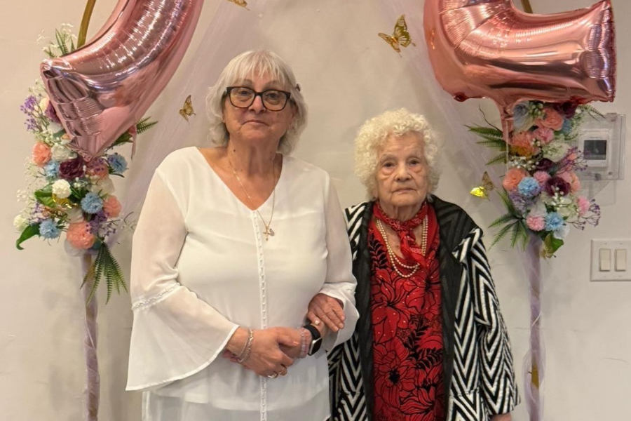 Lily Pace on the left holding another person's arm while between balloons and flowers.